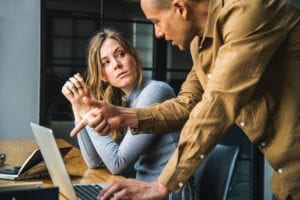 Photo of a man aggressively speaking to a upset female employee